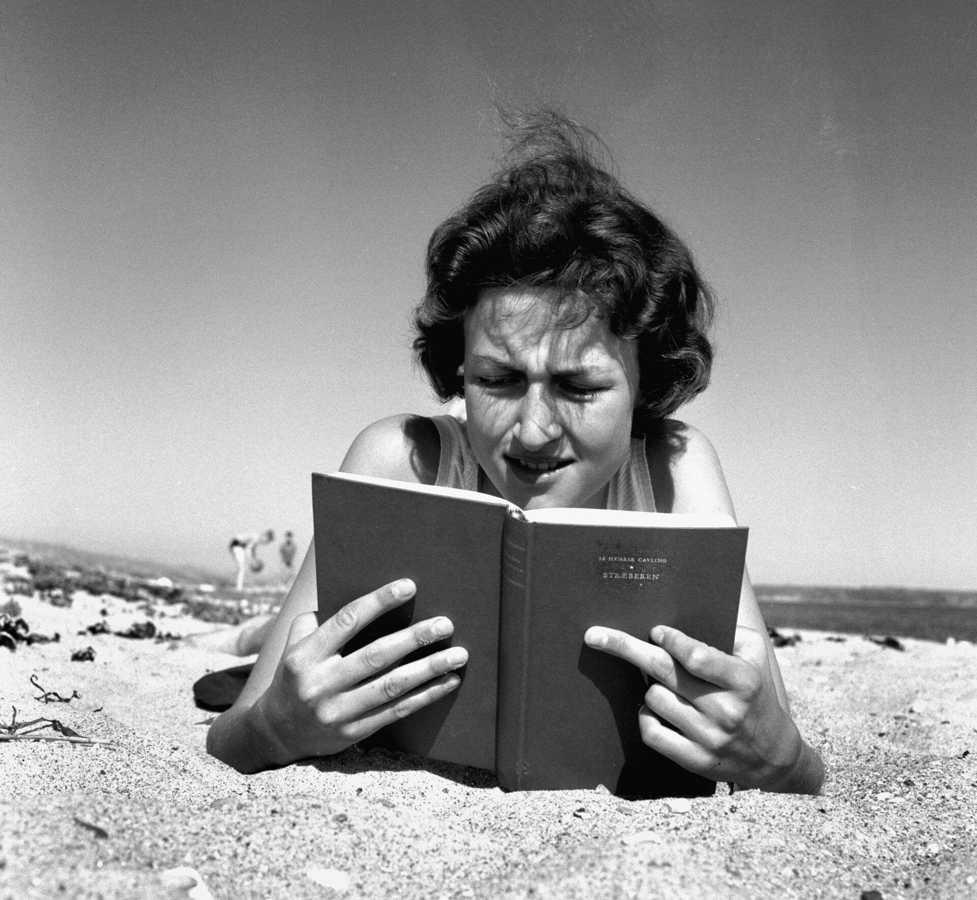 Danmark Dengang 1957."Stræberen"af Ib Henrik Cavling var et hit den sommer.; A young woman on the beach reading the bestseller " Stræberen" ( the climber ) by Ib Henrik Cavling.;