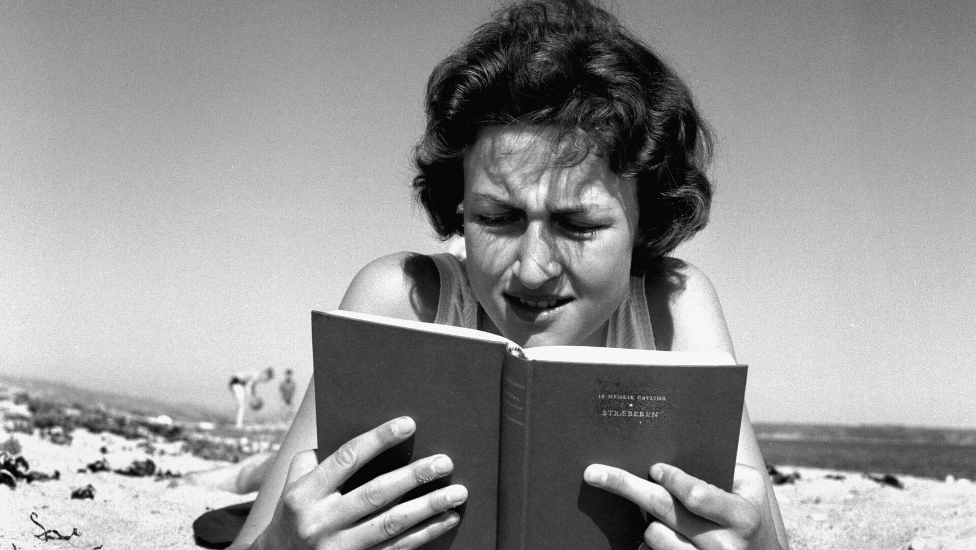 Danmark Dengang 1957."Stræberen"af Ib Henrik Cavling var et hit den sommer.; A young woman on the beach reading the bestseller " Stræberen" ( the climber ) by Ib Henrik Cavling.;