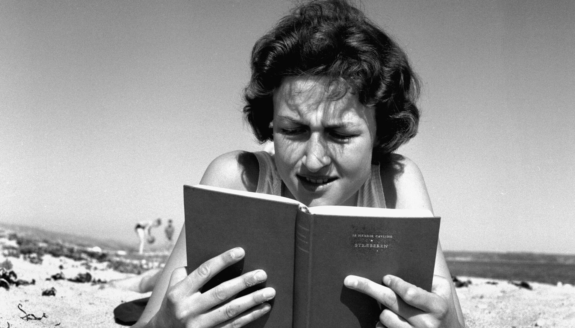 Danmark Dengang 1957."Stræberen"af Ib Henrik Cavling var et hit den sommer.; A young woman on the beach reading the bestseller " Stræberen" ( the climber ) by Ib Henrik Cavling.;